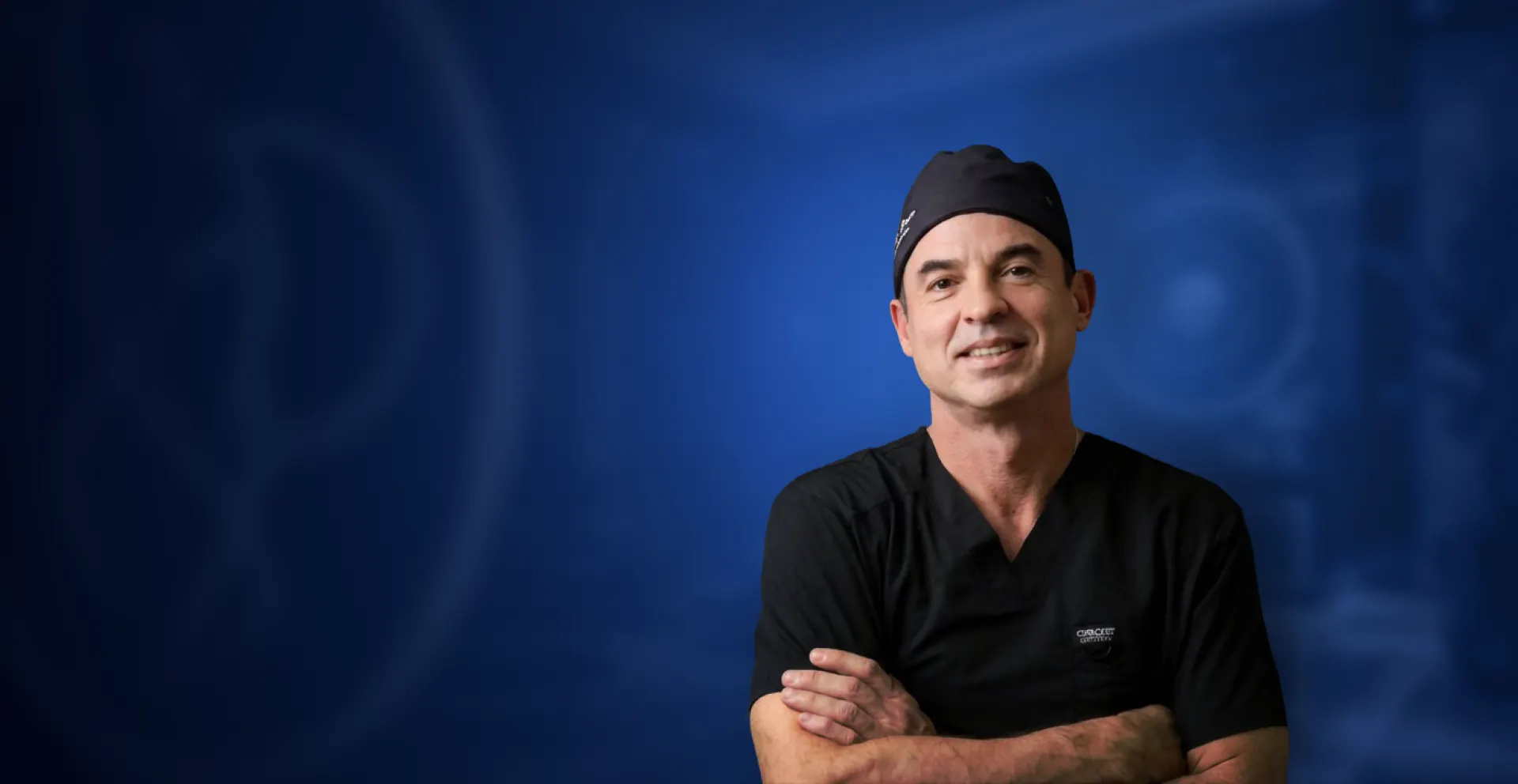 Dr. Edson Prata Jr., cirurgião plástico, sorrindo de touca e uniforme cirúrgico